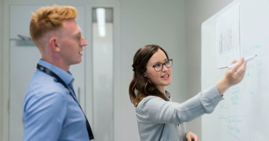 Two business people using a whiteboard to decide which VoIP service will be best for their business